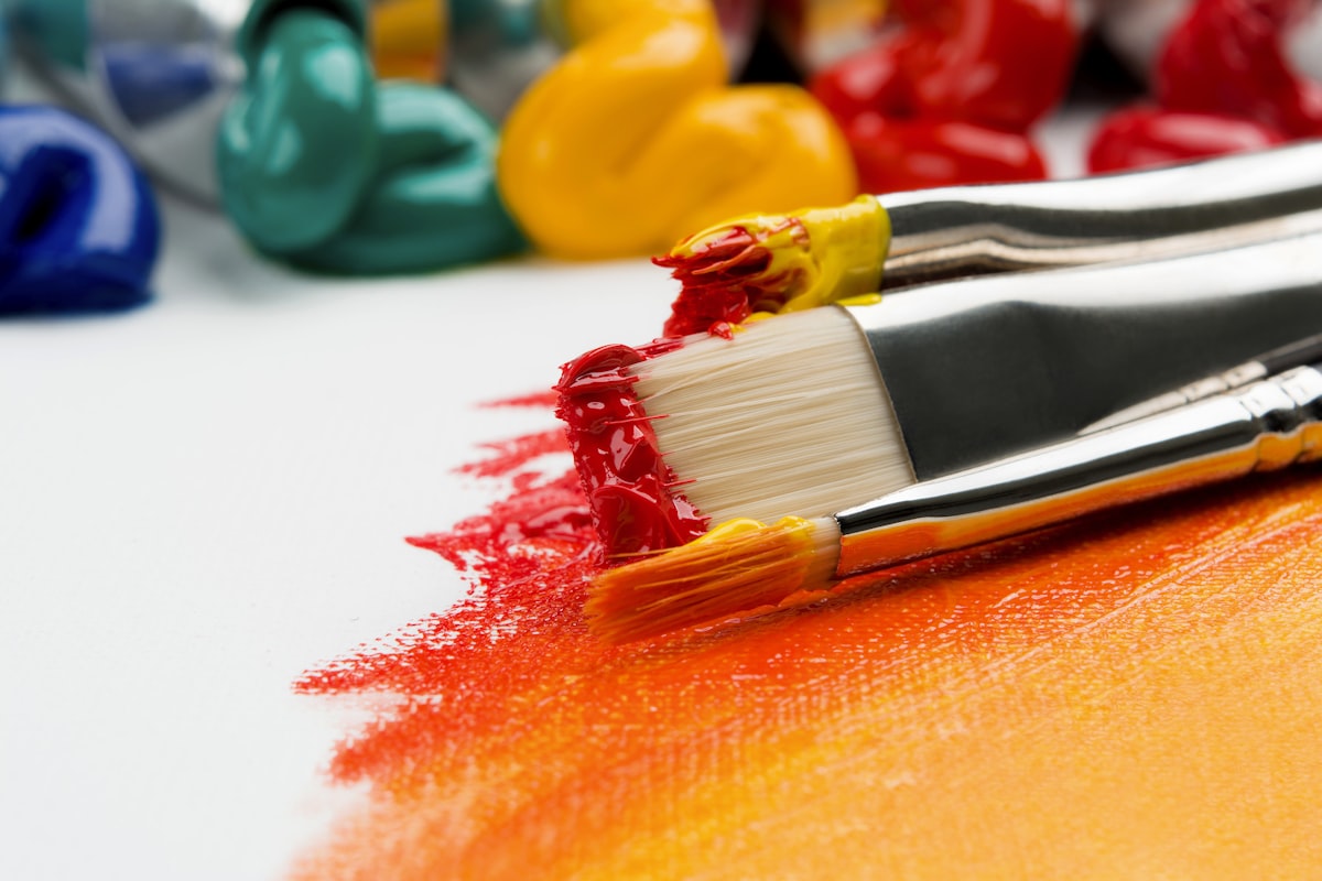 パレットに広げた絵の具と、キャンバスに色をのせる筆